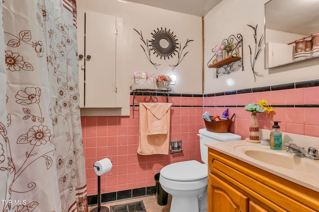 bathroom featuring tile flooring, large vanity, toilet, and tile walls