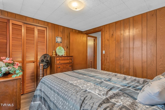 bedroom with wooden walls, a closet, and hardwood / wood-style floors