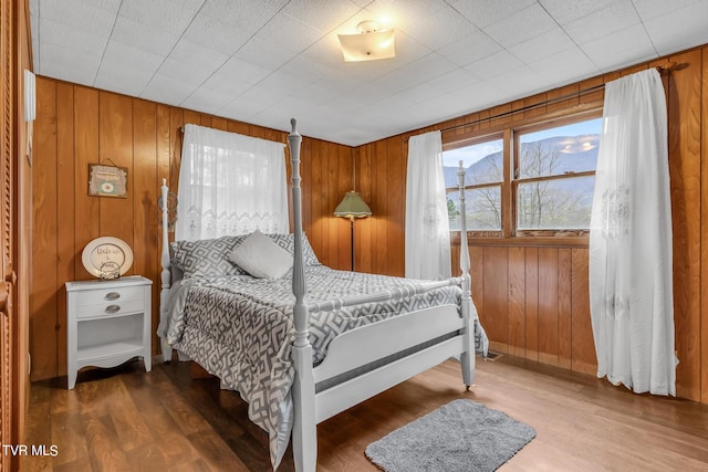 bedroom with hardwood / wood-style floors and wooden walls