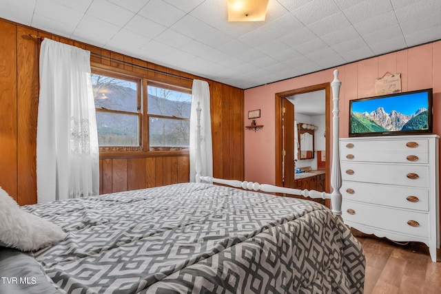 bedroom featuring wooden walls and hardwood / wood-style floors