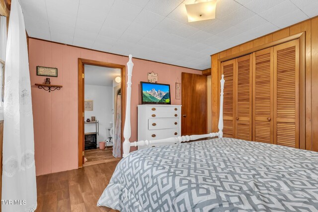 bedroom featuring wood-type flooring, wooden walls, and a closet