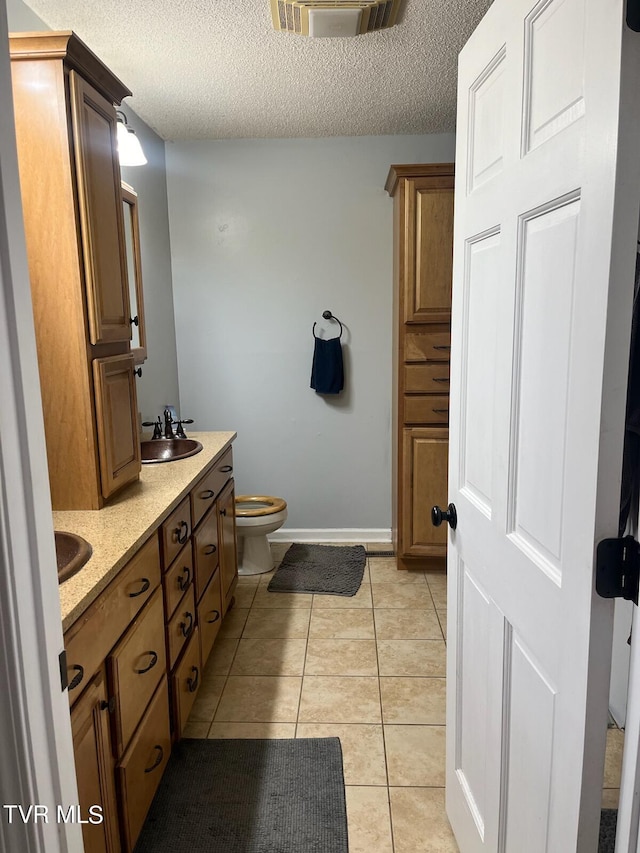 bathroom featuring a textured ceiling, toilet, tile floors, and double sink vanity