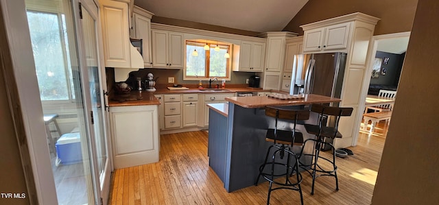 kitchen featuring a kitchen island, a breakfast bar, lofted ceiling, light hardwood / wood-style floors, and sink