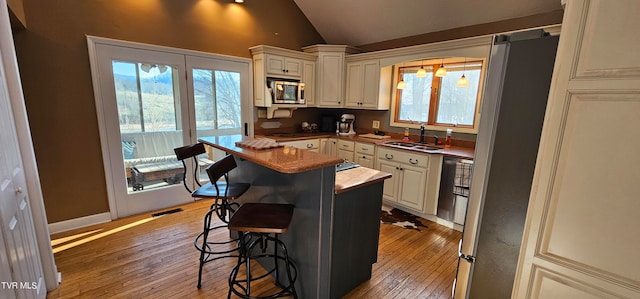 kitchen featuring stainless steel appliances, sink, light hardwood / wood-style flooring, lofted ceiling, and a kitchen island