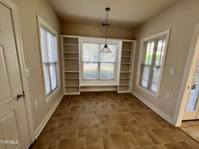 unfurnished dining area featuring dark tile floors and built in shelves