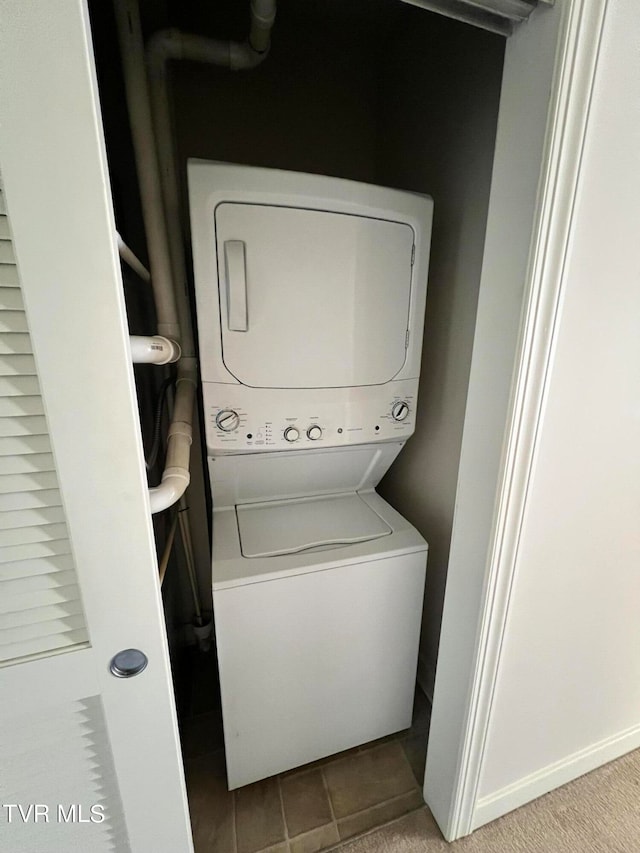 laundry room featuring stacked washer / dryer and light tile floors