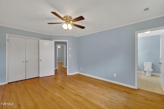 unfurnished bedroom with a closet, light hardwood / wood-style flooring, ceiling fan, and ensuite bath