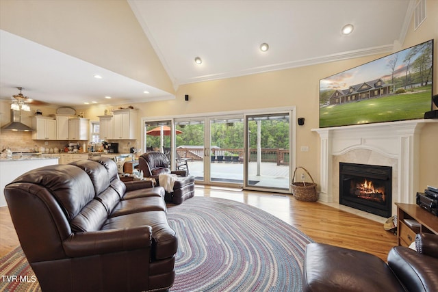 living room with high vaulted ceiling, a fireplace, crown molding, light hardwood / wood-style floors, and ceiling fan