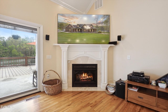 living room featuring crown molding, light wood-type flooring, and a tiled fireplace