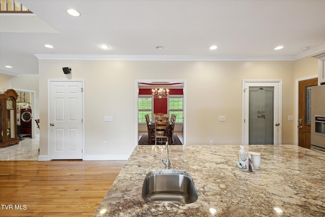 kitchen with light hardwood / wood-style flooring, light stone countertops, an inviting chandelier, and ornamental molding