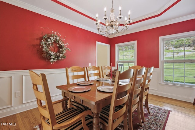 dining room featuring ornamental molding, light hardwood / wood-style flooring, a chandelier, and a raised ceiling