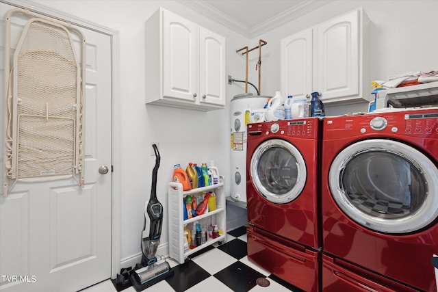 clothes washing area with dark tile floors, crown molding, water heater, washing machine and clothes dryer, and cabinets