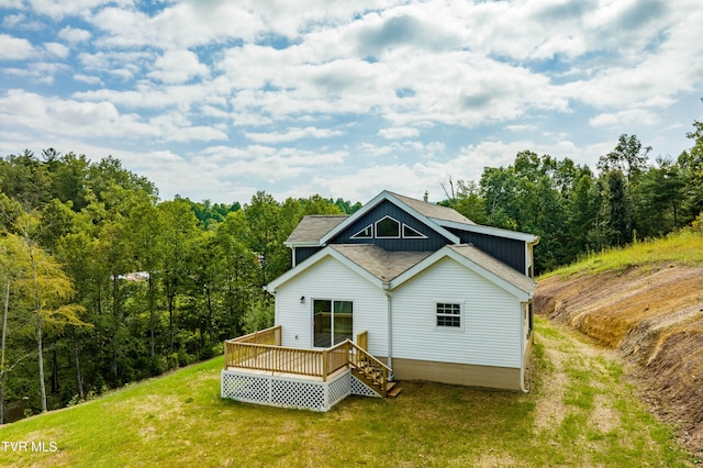 rear view of house featuring a wooden deck and a yard