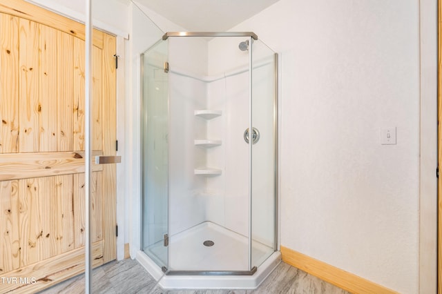 bathroom featuring a shower with shower door and wood-type flooring