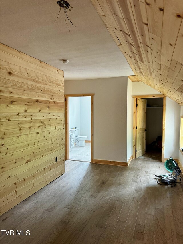 additional living space featuring light hardwood / wood-style floors, vaulted ceiling, wooden ceiling, and wooden walls