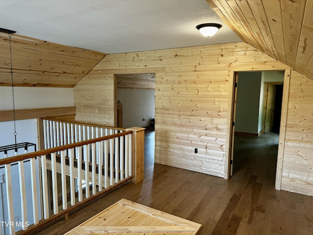 hallway with lofted ceiling, hardwood / wood-style floors, and a textured ceiling