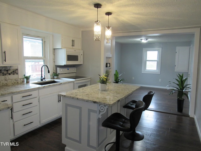 kitchen with a center island, white cabinetry, dark hardwood / wood-style flooring, and white appliances