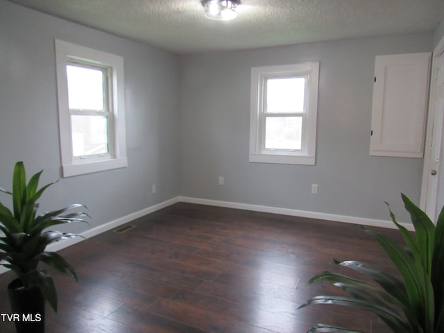 unfurnished room featuring dark hardwood / wood-style flooring and a textured ceiling