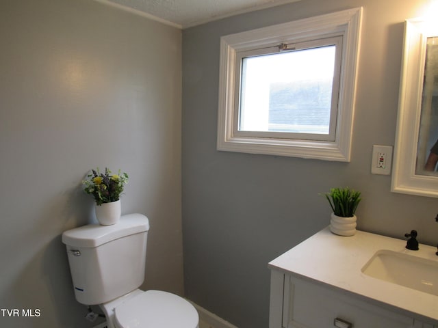 bathroom with vanity with extensive cabinet space, toilet, and a textured ceiling