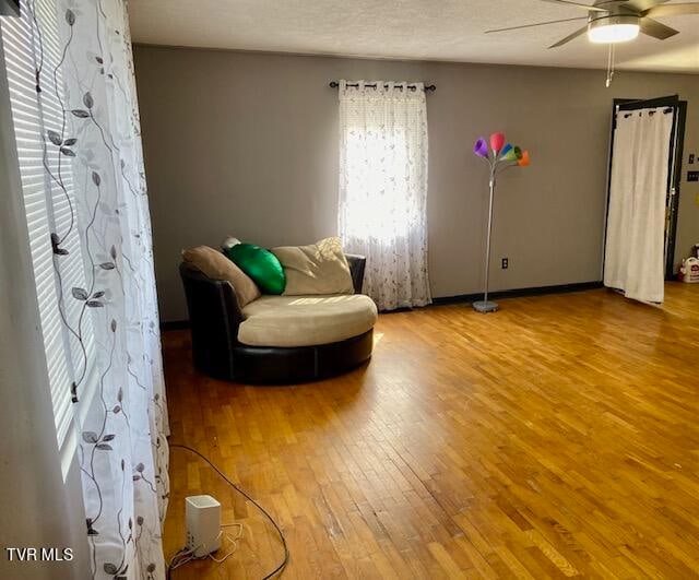 sitting room with ceiling fan and hardwood / wood-style floors