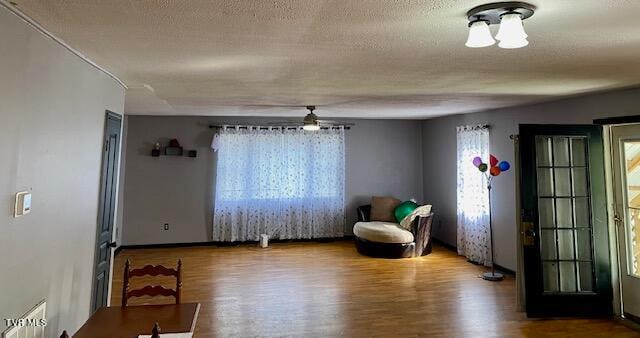 sitting room featuring wood-type flooring, ceiling fan, and a textured ceiling