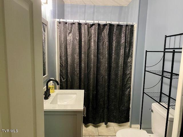 bathroom featuring toilet, tile floors, and vanity