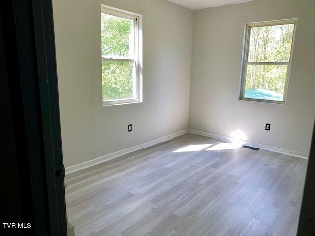 empty room featuring wood-type flooring and a healthy amount of sunlight