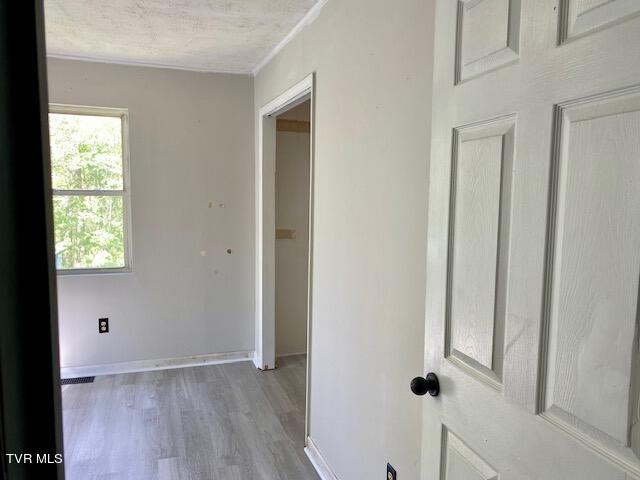 hall with ornamental molding, a healthy amount of sunlight, and hardwood / wood-style flooring