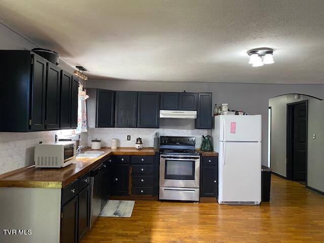 kitchen featuring white appliances, light hardwood / wood-style flooring, sink, tasteful backsplash, and a textured ceiling