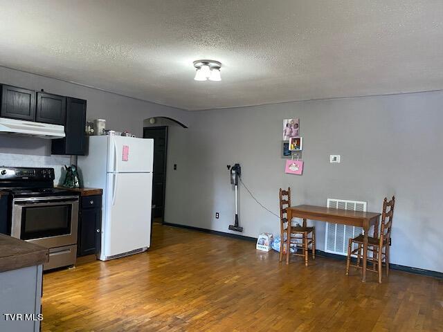 kitchen featuring wood-type flooring, white refrigerator, electric stove, a textured ceiling, and exhaust hood