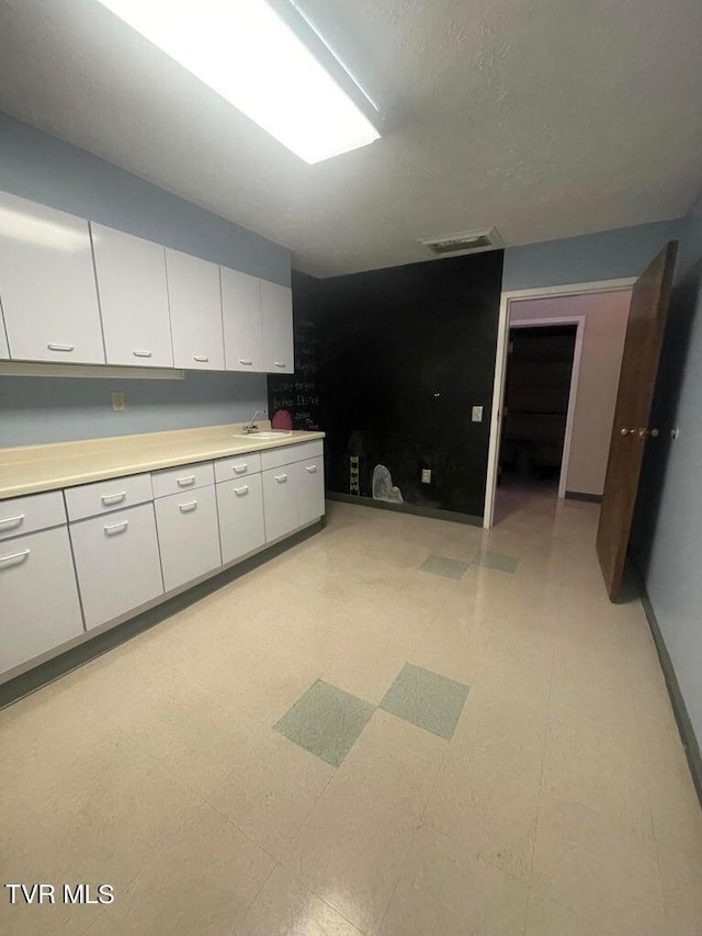 kitchen featuring sink, white cabinetry, and light tile floors