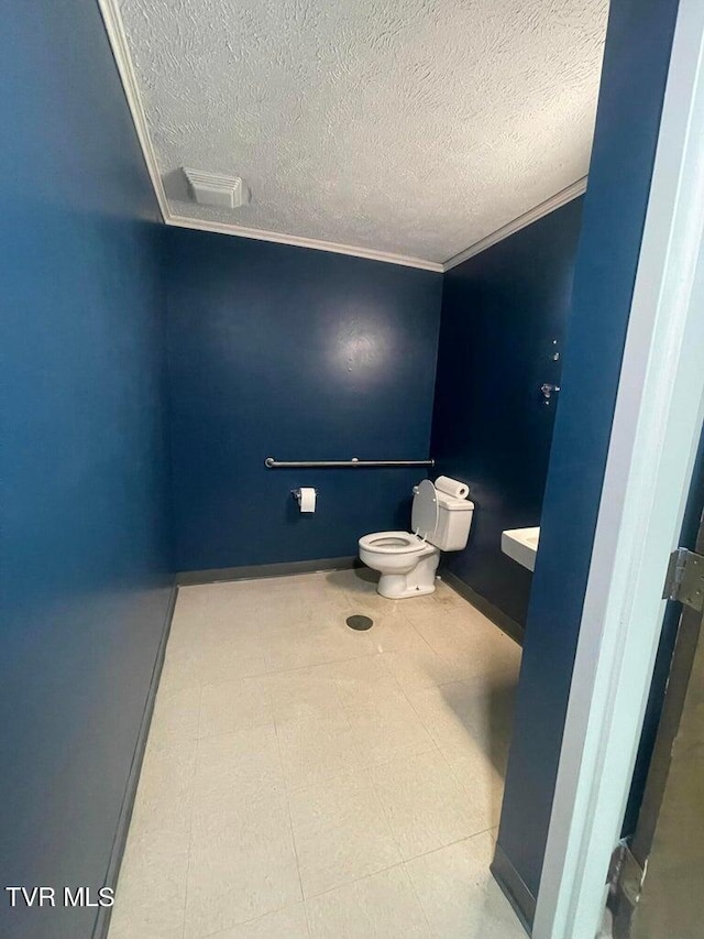 bathroom with tile flooring, crown molding, toilet, and a textured ceiling