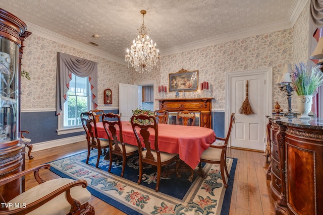 dining space with a textured ceiling, hardwood / wood-style floors, and crown molding