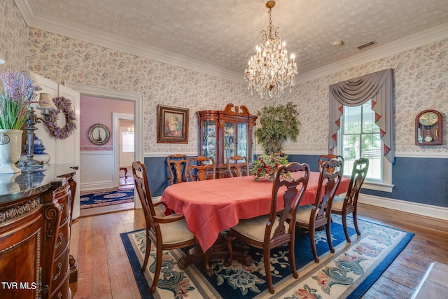 dining room with a chandelier, ornamental molding, dark hardwood / wood-style floors, and a textured ceiling