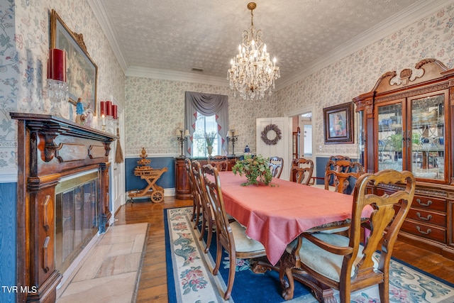 dining area with hardwood / wood-style flooring, ornamental molding, a notable chandelier, and a textured ceiling