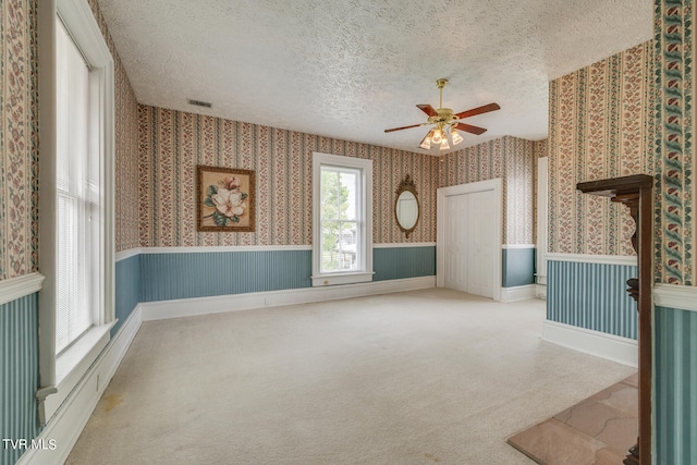 spare room with a textured ceiling, ceiling fan, and carpet flooring