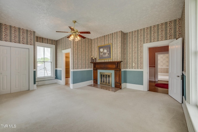 unfurnished living room with ceiling fan, carpet, and a textured ceiling