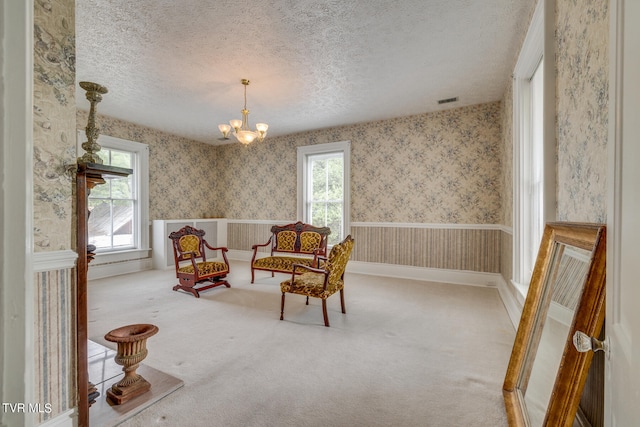 sitting room with a textured ceiling, a notable chandelier, and carpet flooring