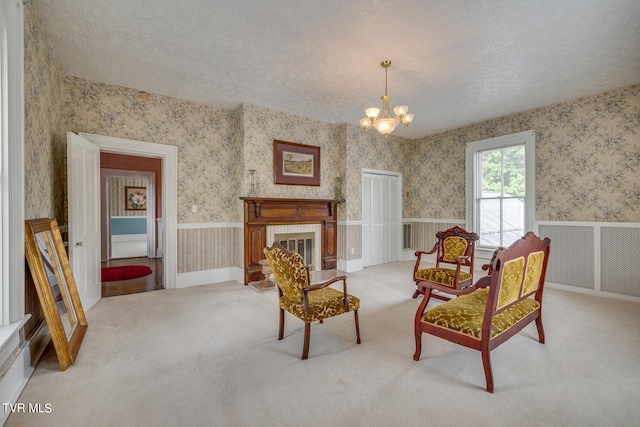 living area with a chandelier, light carpet, and a textured ceiling