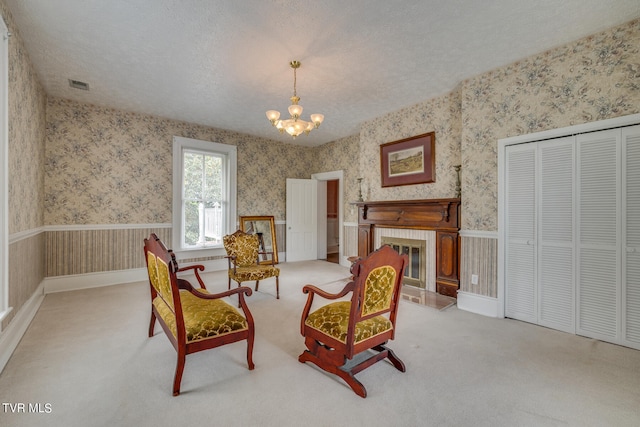 living area featuring a textured ceiling, carpet, an inviting chandelier, and a tiled fireplace