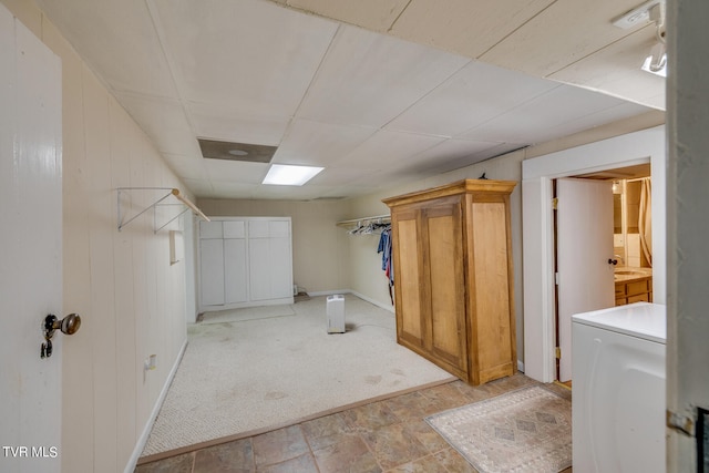 basement featuring a drop ceiling, washer / clothes dryer, and light tile floors