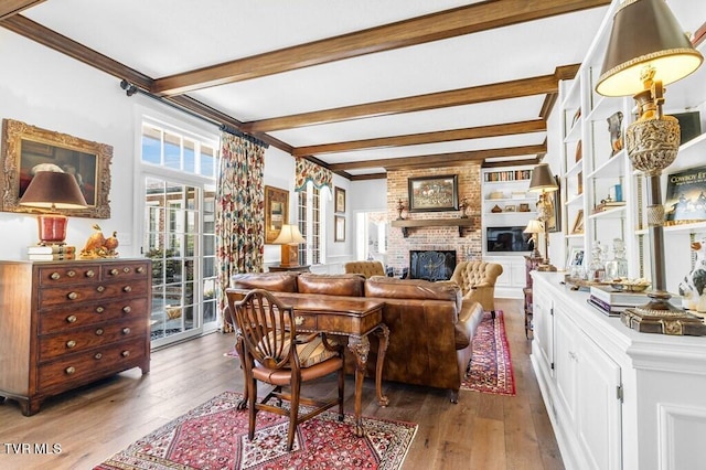 dining space with beamed ceiling, brick wall, a fireplace, and hardwood / wood-style flooring