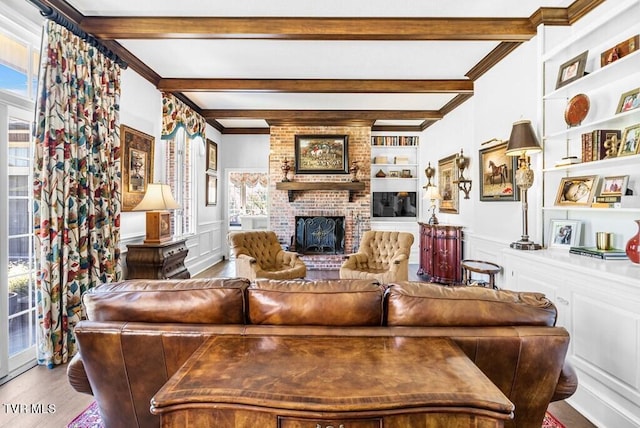 living room featuring built in features, a fireplace, beamed ceiling, and hardwood / wood-style flooring