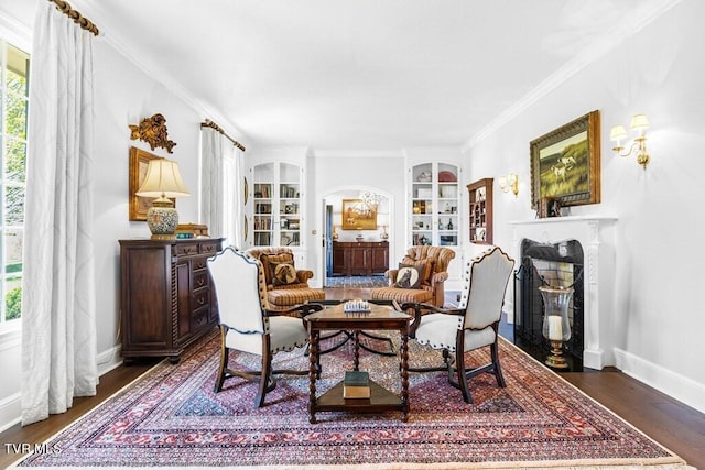 dining room with dark wood-type flooring, built in shelves, ornamental molding, and a healthy amount of sunlight