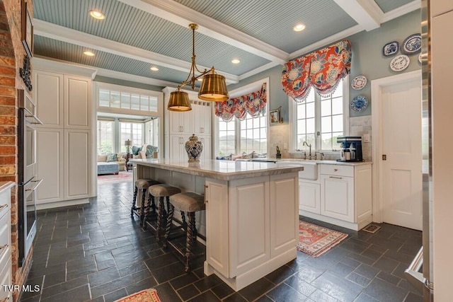 kitchen with a kitchen island, white cabinetry, and a healthy amount of sunlight