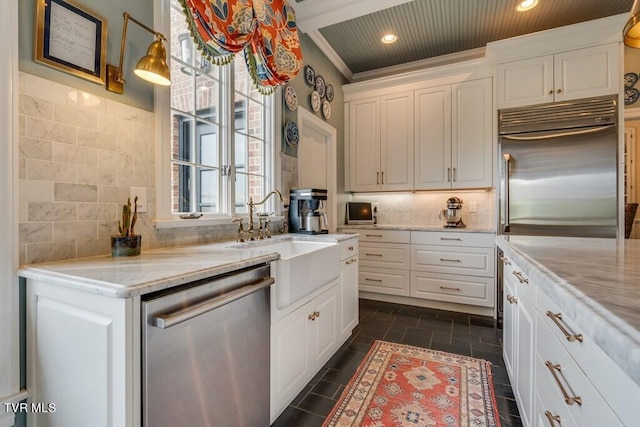 kitchen with stainless steel appliances, white cabinets, decorative backsplash, ornamental molding, and light stone countertops