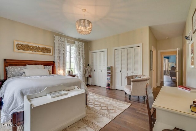 bedroom featuring two closets, a chandelier, and hardwood / wood-style flooring