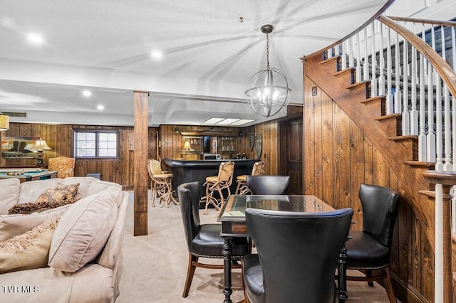 carpeted dining room featuring bar, wooden walls, and a notable chandelier