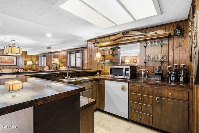 kitchen with wood walls, sink, light tile patterned floors, and kitchen peninsula