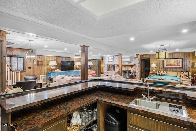 interior space featuring brick wall, wood walls, a textured ceiling, and a brick fireplace